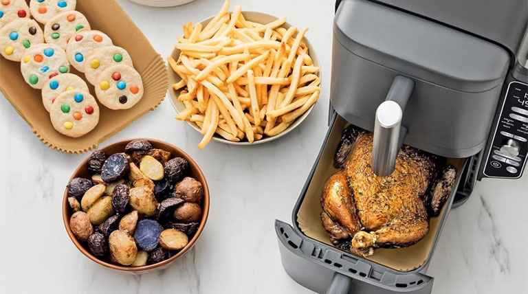 معرفی سرخ کن بدون روغن دو قلو نینجا مدل SL451 سرخ کن بدون روغن دو قلو نینجا مدل SL451 محصولی خلاقانه از برند نینجا است که دارای طراحی منحصر به فرد است. این دستگاه دارای دو طبقه با 2 سبد در هر طبقه می‌باشد که به شما امکان می‌دهد تا 4 نوع غذای مختلف را همزمان بپزید و نیازهای غذایی افراد خانواده را بهتر برطرف کنید. با توان 2470 وات، این سرخ کن سرعت پخت غذاها را افزایش می‌دهد و شما از آشپزی بیشتر لذت می‌برید. ویژگی‌های هوشمند این دستگاه شامل عنصر گرمایش عقب و فن‌های تنظیم هوشمند هستند که باعث می‌شوند هر غذایی به طور یکنواخت و کامل پخته شود. این سرخ کن نینجا SL451 آشپزی را ساده‌تر و کارآمدتر می‌کند و با وجود فناوری‌های پیشرفته، پخت غذاها را به طور ترد و یکنواخت تضمین می‌کند. یکی از مزایای این محصول، مصرف کم انرژی آن است که به مقایسه با اجاق گاز، کمتر انرژی مصرف می‌کند و آن را به یک گزینه کم مصرف تبدیل می‌کند. از ویژگی‌های مهم این دستگاه می‌توان به دکمه انتخاب برنامه، سوییچ بین محفظه‌های ۱ و ۲، تنظیم دما و زمان، پخت همزمان ۴ وعده در ۲ سبد و تنظیمات مشابه بر روی هر دو سبد اشاره کرد. انواع روش‌های پخت با لذت از 6 روش پخت مختلف استفاده کنید، از جمله سرخ‌کردن با حرارت بالا، سرخ‌کردن و سرخ شدن، پختن و کباب کردن، پختن، جوشاندن و خشک کردن و دوباره گرم کردن. با استفاده از سرخ‌کن چندمنظوره نینجا، می‌توانید به راحتی و سریع انواع غذاهای لذیذ مانند مرغ، ماهی، میگو، سیب زمینی و قارچ سرخ‌کن، مرغ، بادمجان کبابی، غذاهای گیاهی، سبزیجات، کلم بروکلی، اسفناج، اسنک، پیتزا، چیپس میوه، انواع کیک، کاپ‌کیک، شیرینی و غیره را آماده کنید. با عدم استفاده از روغن در پخت غذاها، می‌توانید به راحتی انواع غذاهای سرخ شده را بدون نگرانی از افزایش وزن و آسیب به سلامتی مصرف کنید. روش‌های هماهنگ و تطبیق با استفاده از سرخ‌کن نینجا مدل double stack sl451، می‌توانید 2 غذای مختلف را در دماها و زمان‌های گوناگون پخت کنید و همزمان آماده شوند. هنگامی که می‌خواهید چندین غذا با دما و زمان‌های پخت متفاوت را همزمان آماده کنید، روش هماهنگ را انتخاب کنید. اگر چند غذا دارید که شرایط پخت آن‌ها یکسان است، بعد از تنظیم دما و زمان برای یکی از سبدها، نیازی نیست دما و زمان را برای سبد دیگر جداگانه تنظیم کنید. فقط کافیست دکمه Match را انتخاب کنید تا تنظیمات سبد اول روی سبد دوم کپی شود. ترمومتر هوشمند دیجیتال هنگام استفاده از سرخ‌کن نینجا با فناوری Smart Cook، غذا عالی می‌شود. این به این دلیل است که ترمومتر هوشمند دیجیتال به طور مداوم دما و درجه پخت غذا را کنترل می‌کند و همواره دقیق و صحیح عمل می‌کند تا نتایج بی‌نقصی بدست آید. بدنه یکپارچه سرخ کن دو قلو مدل SL451 نینجا سرخ کن دو قلو نینجا مدل SL451 با طراحی منحصر به فرد خود، به خوبی توانسته است انتقادات زیادی را به خود جلب کند و از طرفداران زیادی برخوردار شود. بدنه این دستگاه از جنس پلاستیک محکم و با کیفیت ساخته شده است. این سرخ کن با طراحی خاص خود توانسته است نسبت به سایر مدل‌های مشابه، 30 درصد فضای کمتری را اشغال کند. این ویژگی سبب شده که این سرخ کن انتخاب مناسبی برای آشپزخانه‌های کوچک باشد که به راحتی در آن جا مخاطبان زیادی دارد. همچنین ظرفیت مناسب آن امکان پخت و پز برای حداکثر 8 نفر را فراهم می‌کند. این دستگاه با ظرفیت 9.5 لیتری، قادر است یک مرغ کامل 1.4 کیلوگرمی را در هر کشوی 4.75 لیتری پزد. ظرفیت بالای آن، این دستگاه را برای خانواده‌های بزرگ و حتی مهمانی‌ها مناسب می‌کند. دو کشو وجودی این امکان را فراهم می‌کند تا چهار غذای متنوع به طور همزمان پخته شود که برای آماده سازی غذاهای متنوع بسیار مناسب است. هر کشو توسط سینی‌های توری به دو طبقه تبدیل شده است تا امکان پخت 4 وعده غذایی را در یک زمان فراهم کند. توانایی هماهنگ‌سازی پخت غذاها و تنظیمات هر کشو به راحتی توسط صفحه نمایش لمسی فوق العاده آسان و قابل استفادهی روی بدنه دستگاه انجام می‌شود. سرخ کن بدون روغن دو قلو نینجا مدل SL451 